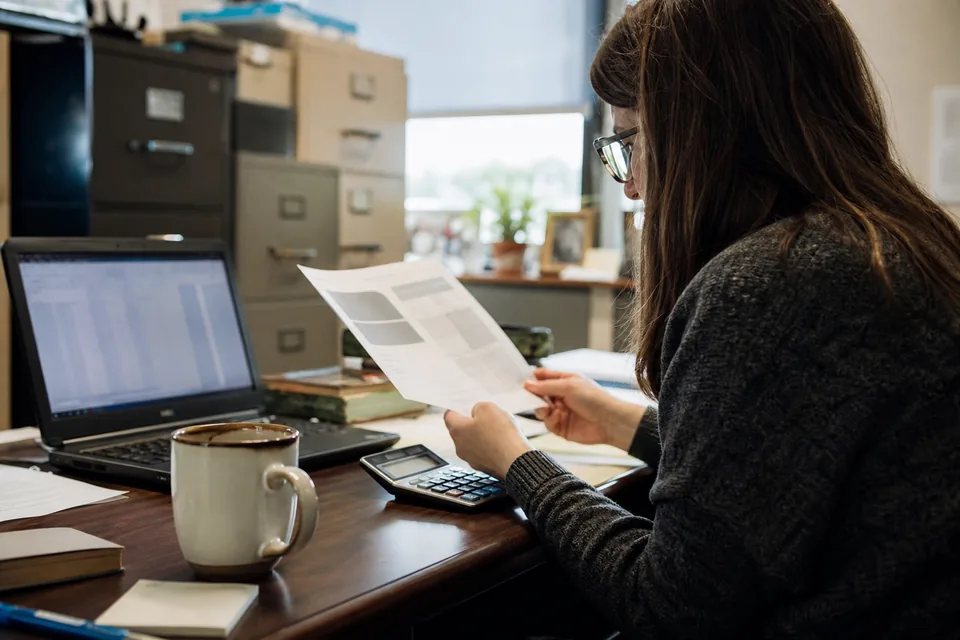 School business manager reviewing a printed software renewal quote with a calculator